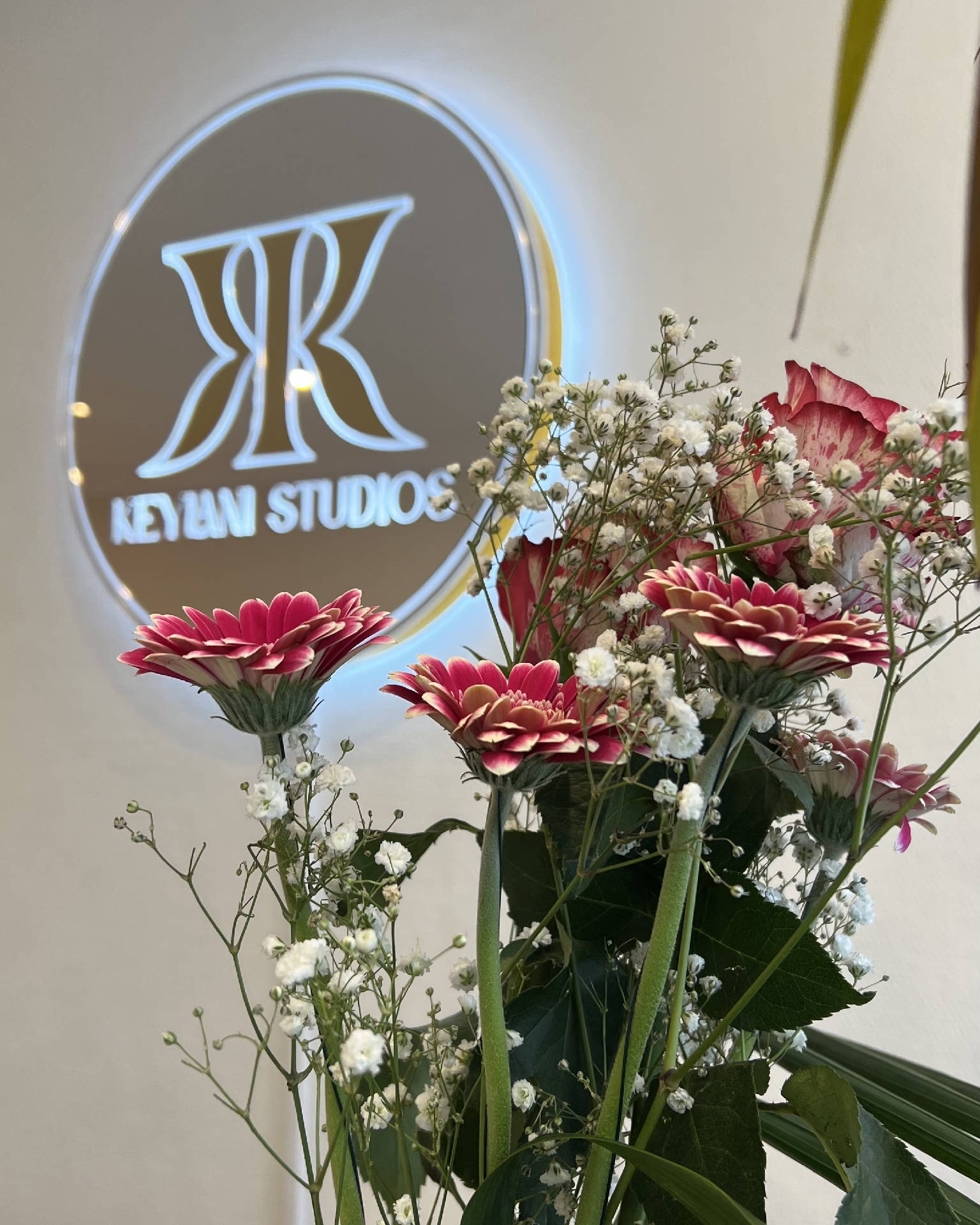 Leuchtendes KK-Logo und Blumen im Studio von Keylani Studios